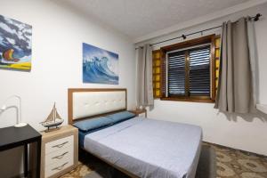 a bedroom with a bed and a desk and a window at Kite & Surf Nomad House in Las Palmas de Gran Canaria