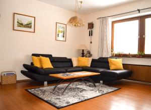 sala de estar con sofá negro y almohadas amarillas en Hotel Garni Wieshof en Kirchberg in Tirol