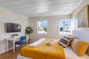 um quarto com uma cama amarela, uma secretária e janelas. em Tropical getaway with coastal charm em Pompano Beach