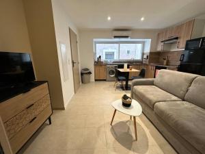 ein Wohnzimmer mit einem Sofa und einem Tisch in der Unterkunft L’amandier - Appartement in Paulhan