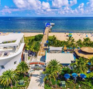 an aerial view of a beach with palm trees and a building at Tropical getaway with coastal charm in Pompano Beach