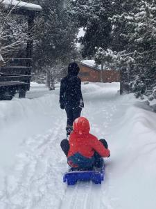 eine Person, die ein Kind auf einem Schlitten im Schnee zieht in der Unterkunft Chalet de montaña in Bolquere