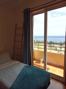 a bedroom with a bed and a view of the ocean at Sunrise Apartment in Caniço