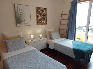 two beds in a room with a window at Sunrise Apartment in Caniço