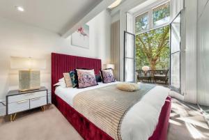 a bedroom with a large bed with a red headboard at Victorian ARCHITECT Flat with Long BALCONY in London