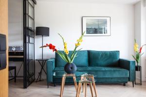 uma sala de estar com um sofá azul e um vaso com flores em Luxurious, Spacious, Modern Gem. Great Location ! em Varsóvia