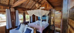- une chambre avec un lit à baldaquin dans une cabine dans l'établissement Divino Tatajuba bungalows, Vista para o mar!, à Tatajuba