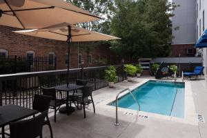 a swimming pool with tables and chairs and an umbrella at Hampton Inn & Suites Gainesville Downtown in Gainesville