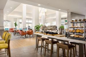 a restaurant with a counter with chairs and tables at Hilton Garden Inn Fort Collins in Fort Collins