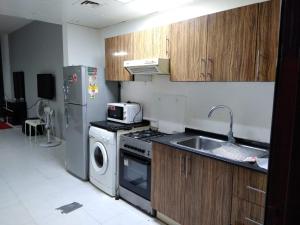 a kitchen with a stove and a sink and a refrigerator at Studio Apartment in Ajman 