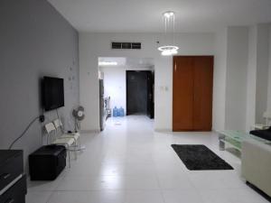 a white living room with a couch and a tv at Studio Apartment in Ajman 