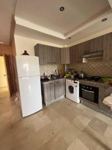 cocina con nevera blanca y lavavajillas en Appartement à savannah beach, residence balnéaire, en Dar Hamida