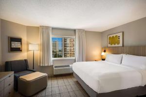 una camera d'albergo con un letto, una sedia e una finestra di Sonesta Simply Suites Jersey City a Jersey City
