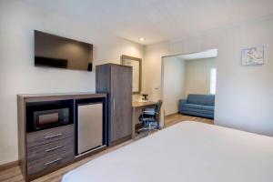 een slaapkamer met een bed en een tv en een bank bij Studio 6 Rosemead, CA in Rosemead