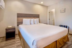 een groot wit bed in een kamer met een nachtkastje bij Studio 6 Rosemead, CA in Rosemead