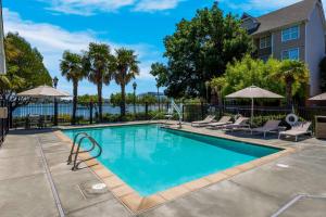 a swimming pool with chairs and umbrellas next to a building at Sonesta ES Suites San Francisco Airport Oyster Point Waterfront in South San Francisco