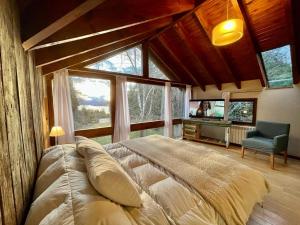 a bedroom with a large bed in a room with windows at Hogar de Montaña in Villa La Angostura