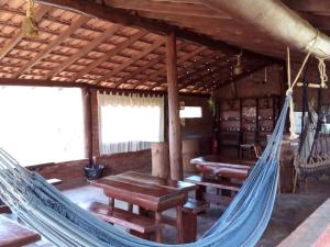 a hammock in a cabin with tables and benches at Pousada e Camping Pé na Trilha in Bueno Brandão