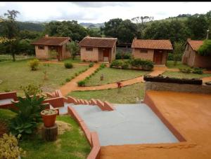 uitzicht op een tuin met huizen op de achtergrond bij Pousada e Camping Pé na Trilha in Bueno Brandão