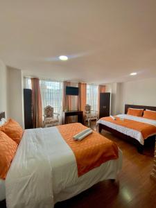 - une chambre avec 2 lits avec des draps orange et blancs dans l'établissement Ayenda Hotel Posada Leon, à Pasto