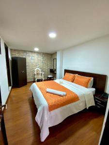 a bedroom with a large bed with an orange comforter at Ayenda Hotel Posada Leon in Pasto