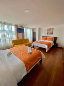 Habitación de hotel con 2 camas y sofá en Ayenda Hotel Posada Leon en Pasto