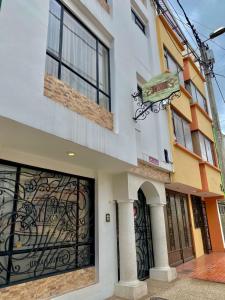 un bâtiment blanc avec un portail et un panneau sur celui-ci dans l'établissement Ayenda Hotel Posada Leon, à Pasto