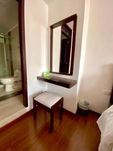a bathroom with a bench and a mirror and a toilet at Ayenda Hotel Posada Leon in Pasto