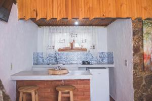 a kitchen with a counter and two stools in it at Chales Boa Vista in Monte Verde