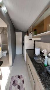 Elle comprend une petite cuisine équipée d'un évier et d'un réfrigérateur. dans l'établissement Apartamento térreo, à Florianópolis
