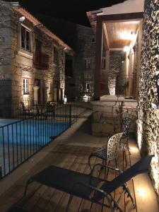 um pátio com cadeiras e uma piscina à noite em Casas do Solar - Guest House - em Almeida