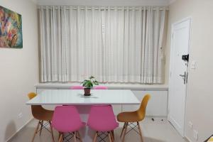 a dining room with a white table and pink chairs at Apartamento encantador- 40 metros da praia e duas quadras do shopping in Santos
