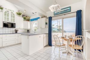 eine Küche mit weißen Schränken sowie einem Tisch und Stühlen in der Unterkunft Berry Nice Beach House in Seal Rock
