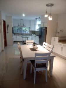 eine Küche mit einem weißen Tisch und Stühlen sowie einem Tisch und einem Chairsktop in der Unterkunft Casa Serena - Casa de Huéspedes in Guadalajara