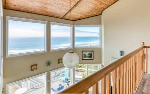 a staircase with large windows and a pendant light at Seas the Day in Lincoln City