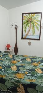 ein Bett mit einer bunten Decke mit einem Bild einer Palme in der Unterkunft Tropical cocoon in Kourou