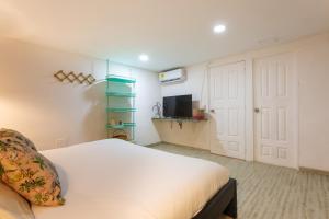 a bedroom with a white bed and a tv at Al Alma Apart-Suites in Cartagena de Indias