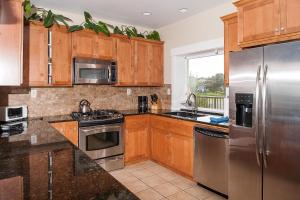 una cocina con armarios de madera y electrodomésticos de acero inoxidable en Michael's Beach Place @ Shoreline Ridge en Newport