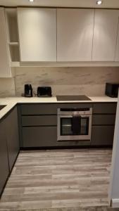 a kitchen with white cabinets and a stove top oven at London City Stay in London