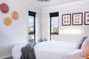 um quarto branco com uma cama branca e janelas em Whale Watcher 1 em Coles Bay