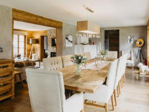 une salle à manger avec une table en bois et des chaises blanches dans l'établissement Chalet-Apartment Alpenrose am Lift, à Kirchberg in Tirol