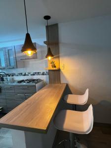 a kitchen with a wooden counter top and two stools at Vive como un local en Popayan in Popayan