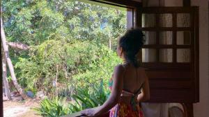 uma mulher olhando pela janela de uma casa em Vila Verde Perto em Lençóis