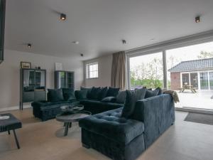 sala de estar con sofá azul y ventana grande en Jonkershof, en Lage Zwaluwe