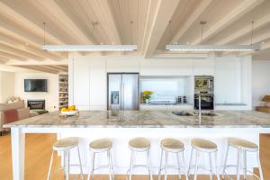 a kitchen with a large island with bar stools at Min Y Mor in Onetangi