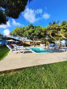 a swimming pool with lounge chairs and a swimming poolvisor at Pousada São Francisco in Cumuruxatiba +37 photos