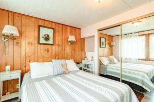 two beds in a room with wood paneled walls at Rockaway Beachhouse in Rockaway Beach
