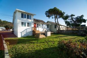 a white house with a porch and a yard at Rockaway Beachhouse in Rockaway Beach