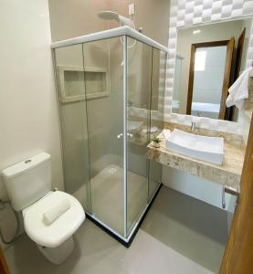 uma casa de banho com um chuveiro, um WC e um lavatório. em Apartamentos Villa dos Diamantes em Porto Seguro