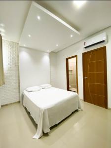 a white bedroom with a bed and a air conditioner at Apartamentos Villa dos Diamantes in Porto Seguro